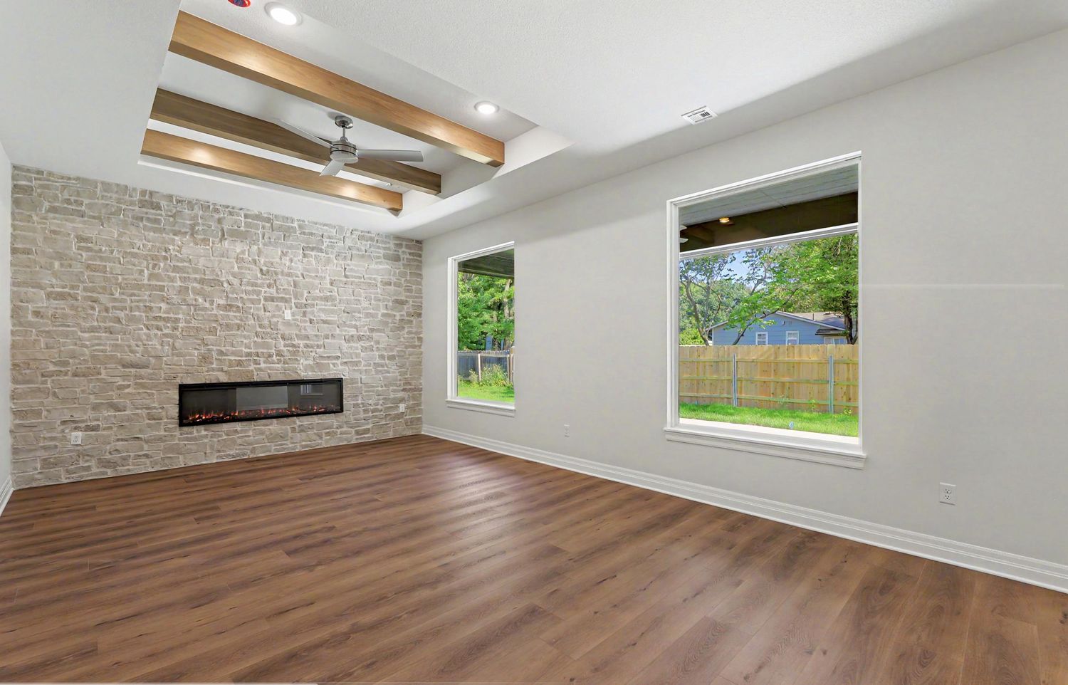 Great room with a stacked-stone fireplace wall and stained timber ceiling beams in the RJ Castle home at 116 S Byron Road – Wichita, KS