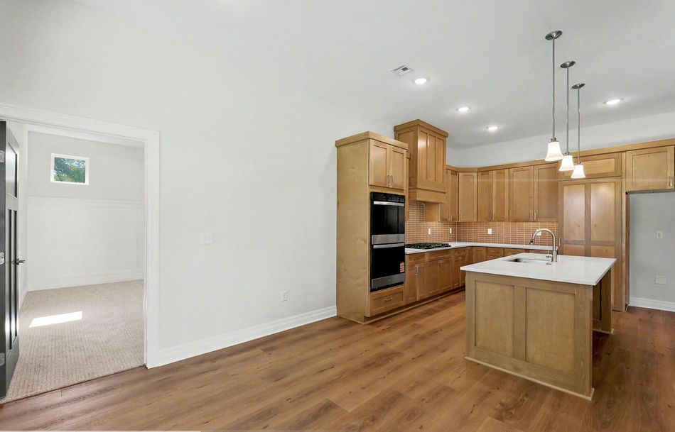 L-shaped kitchen counter run at 116 S Byron Road by RJ Castle Homes with a tile backsplash and a view through to a bedroom – Wichita, KS