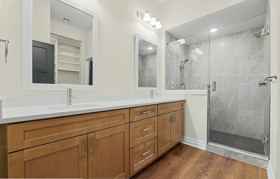 Primary bathroom at 116 S Byron Road by RJ Castle Homes with a double vanity and a marble-tiled walk-in shower behind a glass screen – Wichita, KS