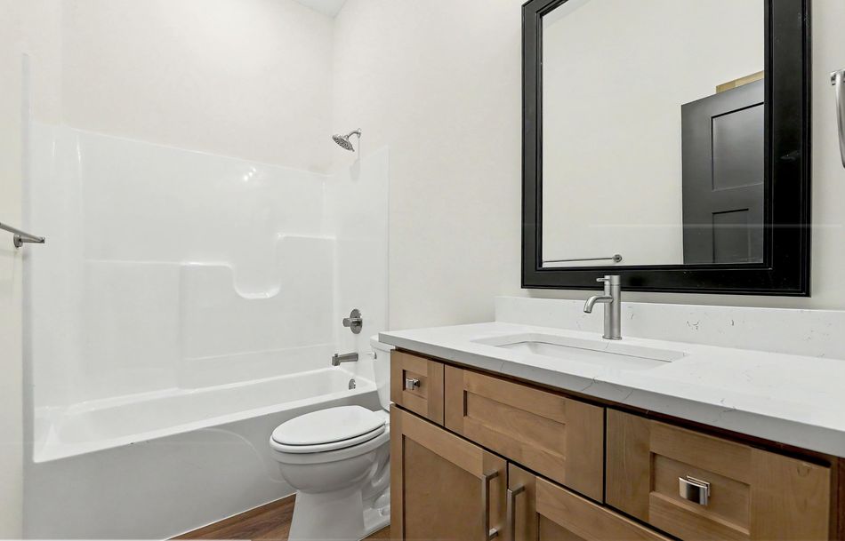 Secondary bathroom at 116 S Byron Road by RJ Castle Homes with a tub-shower, quartz vanity top and a black framed mirror – Wichita, KS