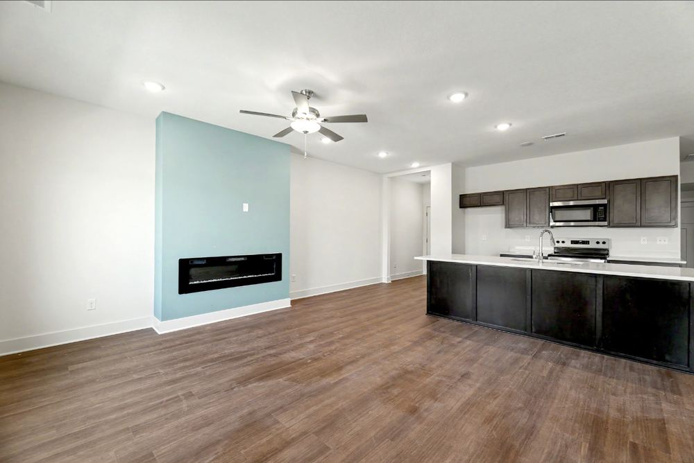 Cedar Crest duplex living room with a linear electric fireplace set into a pale blue accent wall, open to the kitchen – Wichita, KS