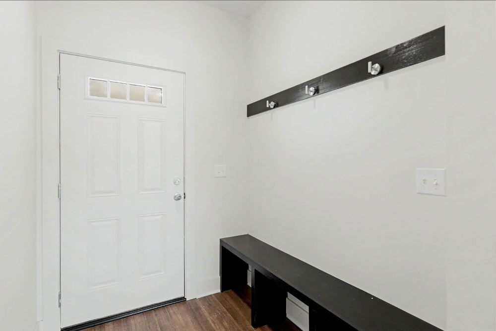 Cedar Crest duplex mudroom with a dark bench, hook rail and side entry door – Wichita, KS