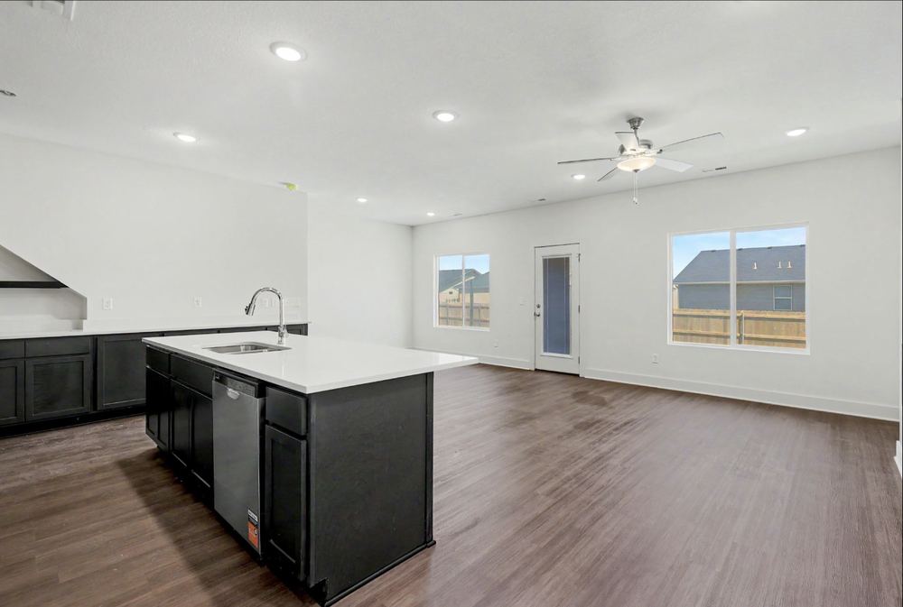 Open-plan kitchen and living room in the Cedar Crest duplex with a quartz-look island, dark cabinetry and wood-look LVP flooring – Wichita, KS