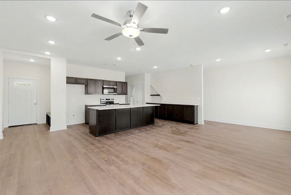 The second Cedar Crest unit with the same island kitchen layout and cabinetry on a lighter wood-look LVP floor – Wichita, KS