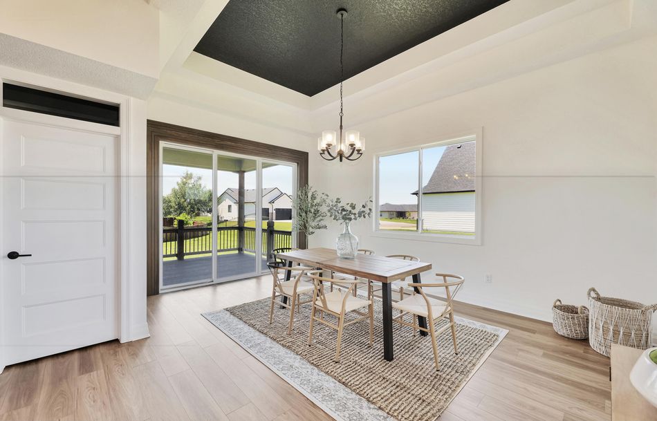 Dining room at 2579 Doris Court under a dark-painted tray ceiling, beside sliding doors onto the covered deck – Wichita, KS