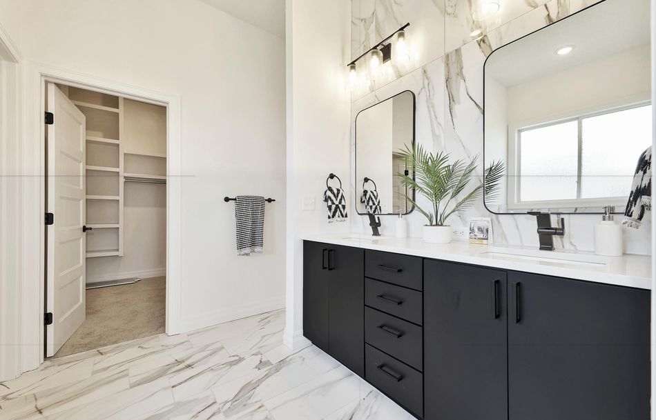 Primary bathroom at 2579 Doris Court with a charcoal double vanity, marble-look floor tile and a walk-in closet beyond – Wichita, KS