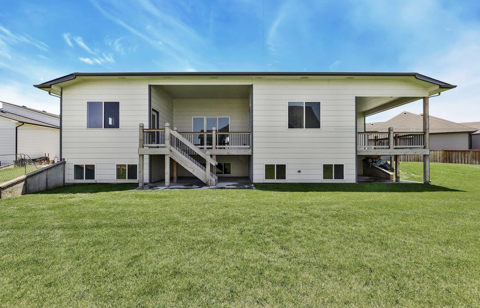 Rear elevation of 2579 Doris Court showing the walkout lower level, the raised deck and stairs down to the lawn – Wichita, KS