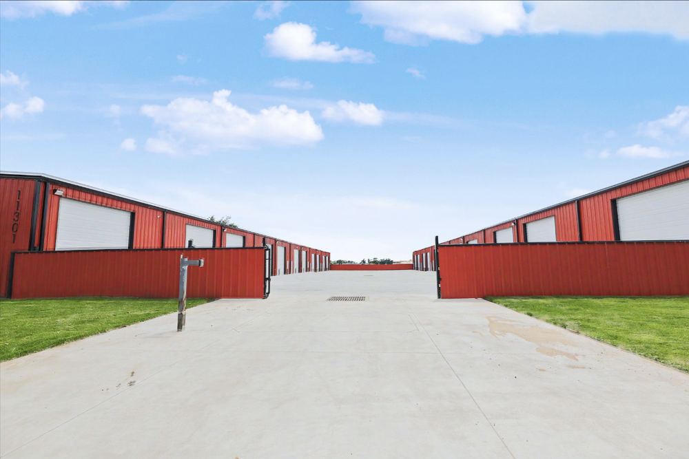Concrete drive running between two rows of red steel Eagle Lux garage condo buildings with the access gates open – Maize, KS
