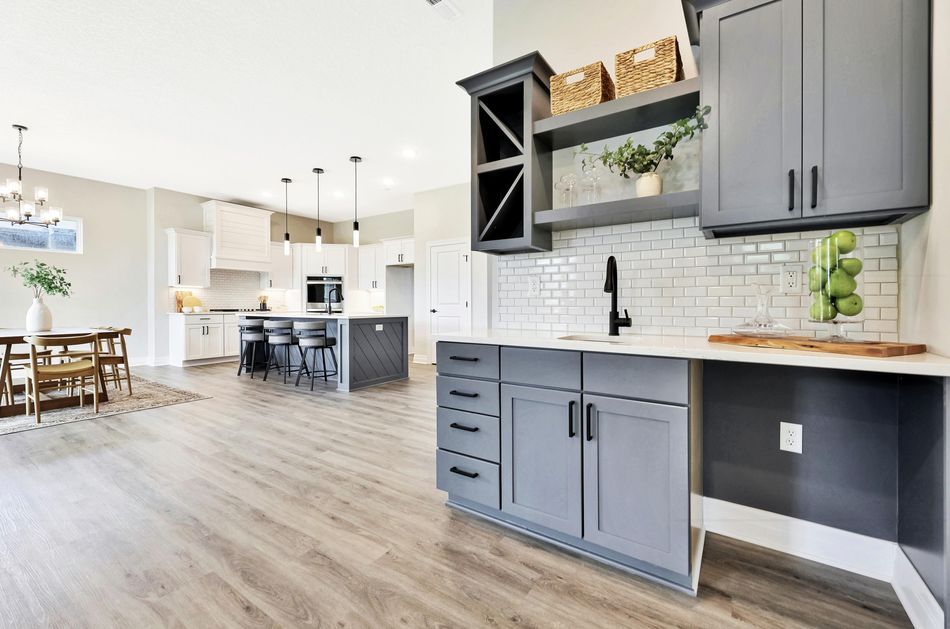 Dining area and built-in wet bar at 4658 W Emerald Bay Court with grey cabinetry and a mirrored tile backsplash – Wichita, KS