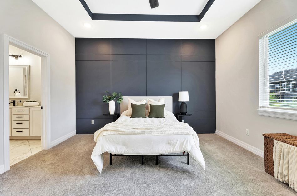 Primary bedroom at 4658 W Emerald Bay Court with a dark panelled accent wall and a tray ceiling – Wichita, KS