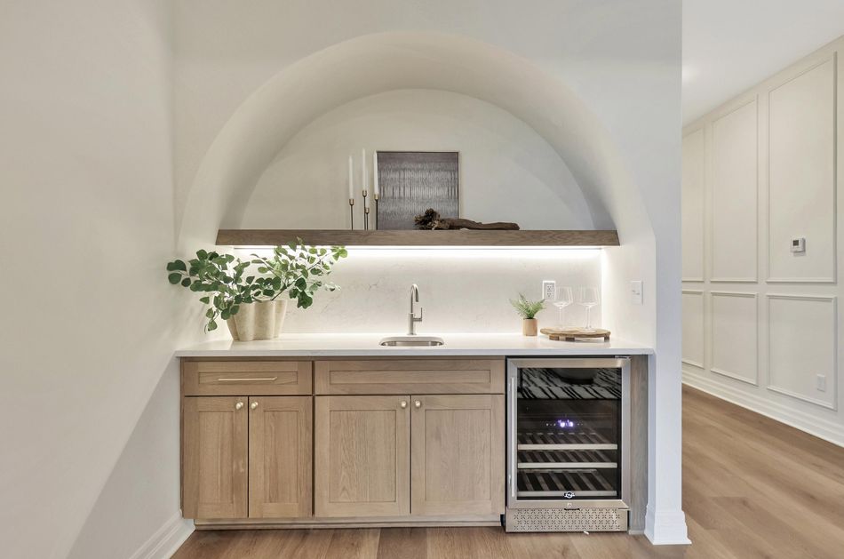 Arched wet bar alcove at 13650 W Homestead Drive with an oak cabinet base, floating shelf and beverage fridge – Colwich, KS