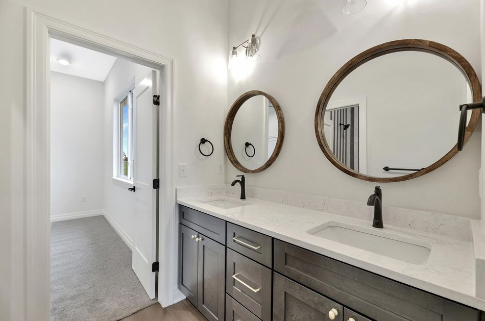 Primary bathroom at 13650 W Homestead Drive with a dark double vanity, quartz top and round timber-framed mirrors – Colwich, KS