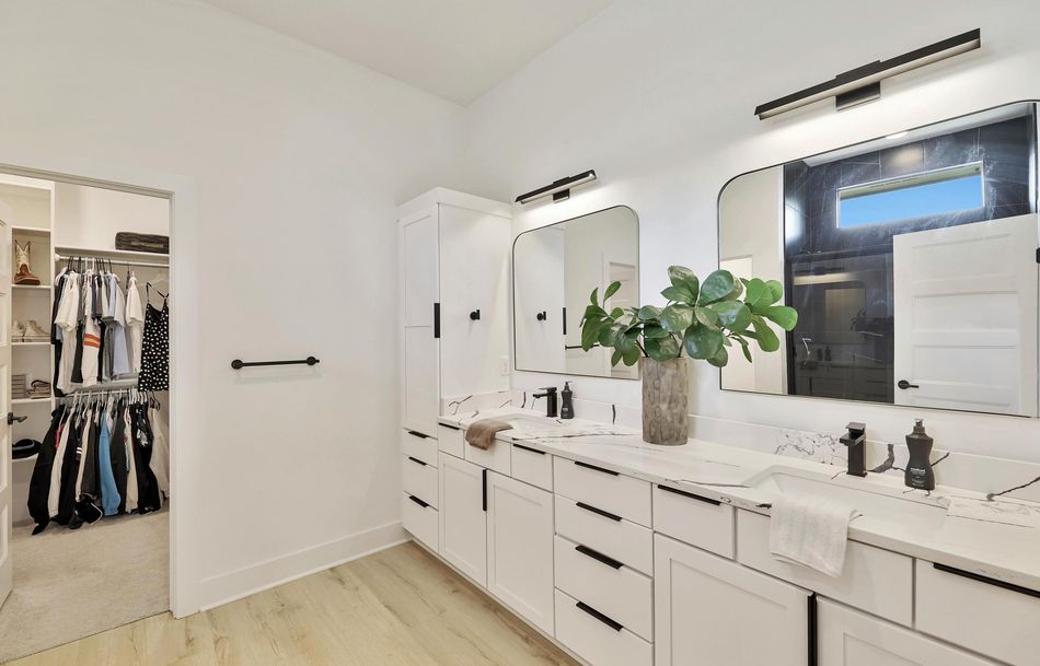Primary bathroom at 5915 W Kollmeyer Court with a long white double vanity, two arched mirrors and a pass-through to the closet – Wichita, KS