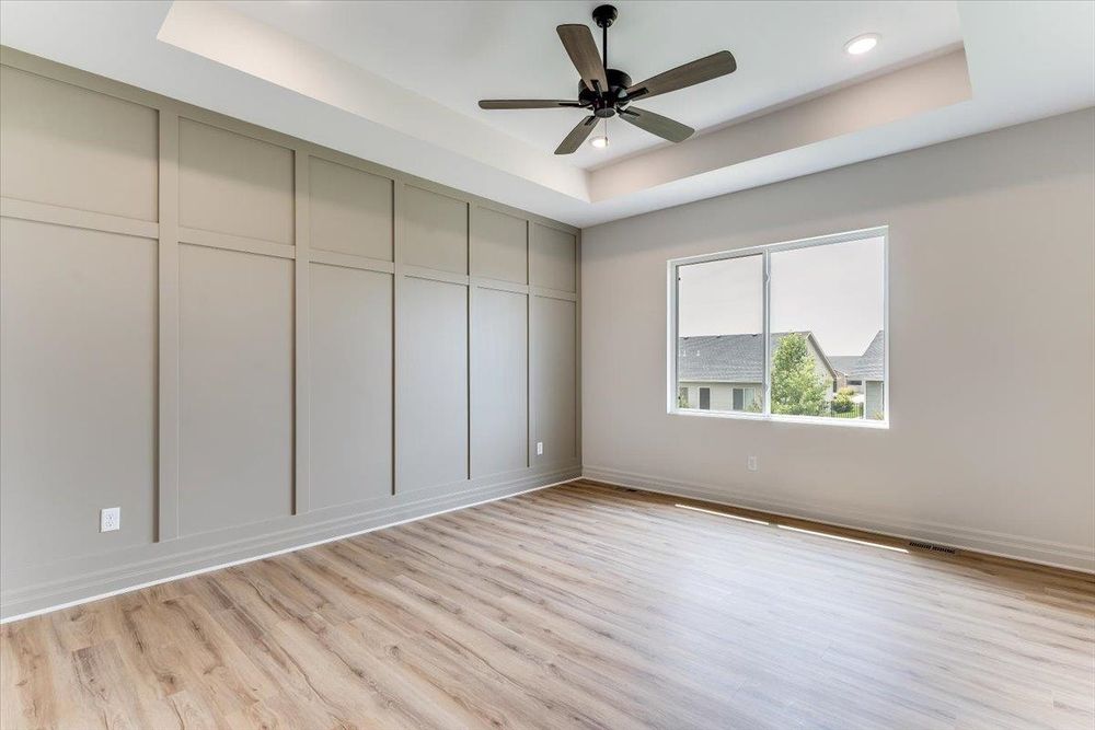 Primary bedroom with a tray ceiling and panelled accent wall at 10515 W Basil St, Wichita, KS