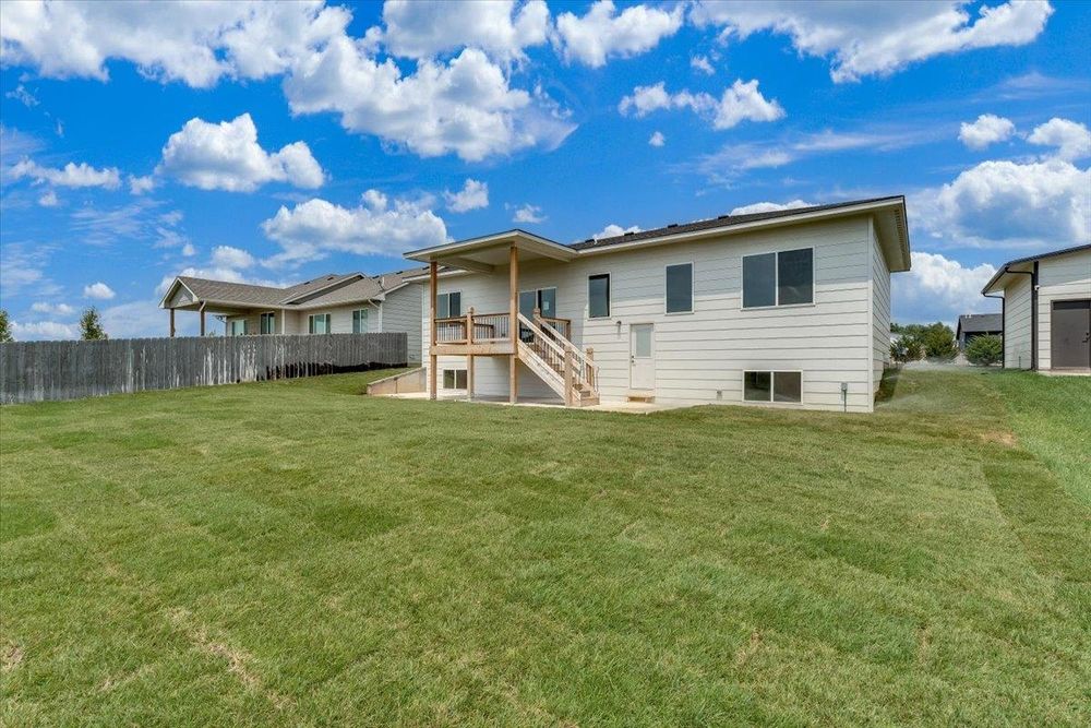 Rear exterior with a covered deck over the sodded back yard at 10515 W Basil St, Wichita, KS