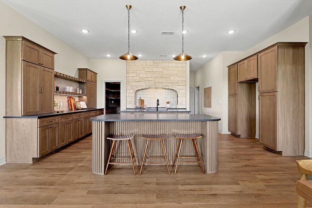 Kitchen with a fluted island, wood cabinetry and a stone range surround at 24465 W Stonebottom Ct near Goddard, KS