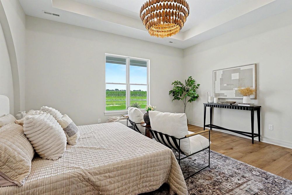Primary bedroom with a tray ceiling and statement chandelier at 24465 W Stonebottom Ct near Goddard, KS