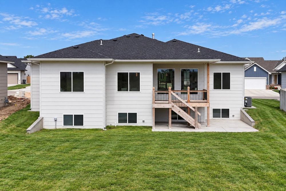Rear exterior with a covered deck stepping down to a ground-level patio at 5857 N St. Paul Ct, Wichita, KS