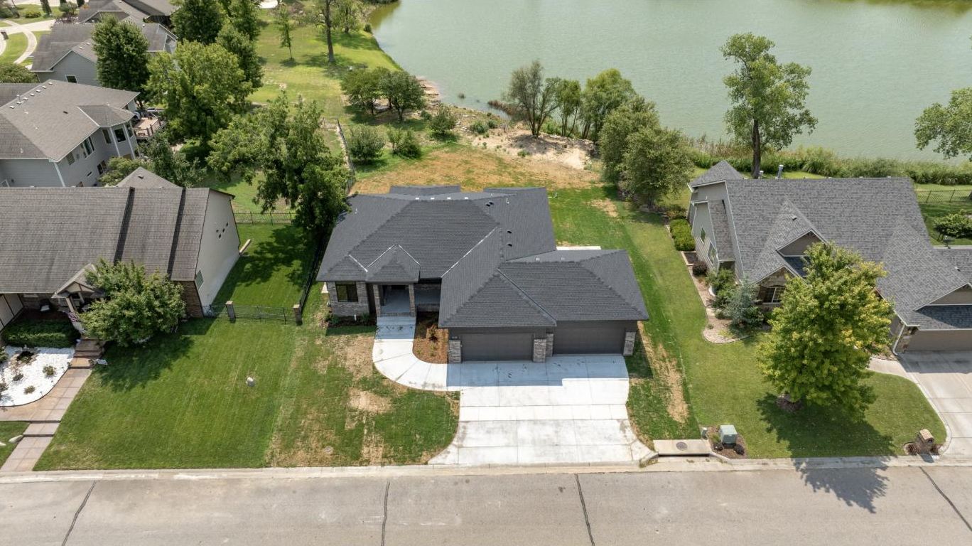 Aerial view of the lakefront custom home built by RJ Castle Homes at 3117 Sunflower Drive, its lawn running down to the water – Derby, KS