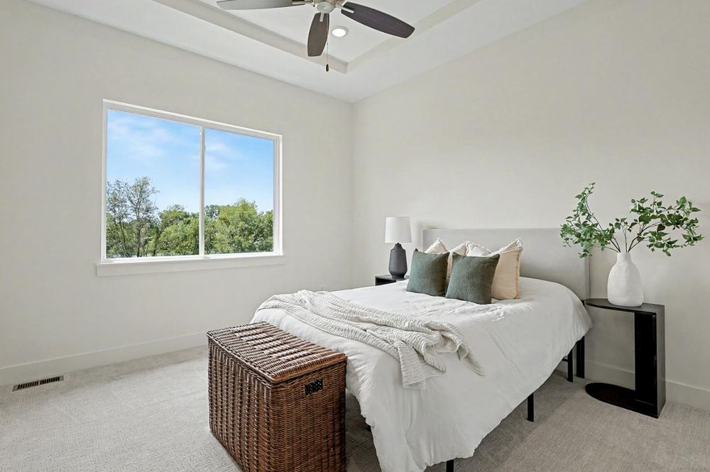 Bedroom at 3117 Sunflower Drive with a tray ceiling, ceiling fan and a picture window onto the tree line – Derby, KS