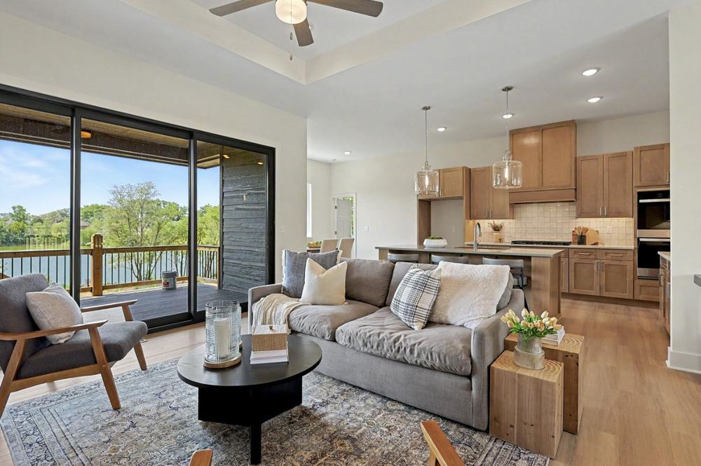 Great room at 3117 Sunflower Drive open to the kitchen, with a sliding glass wall onto the covered deck and the lake beyond – Derby, KS