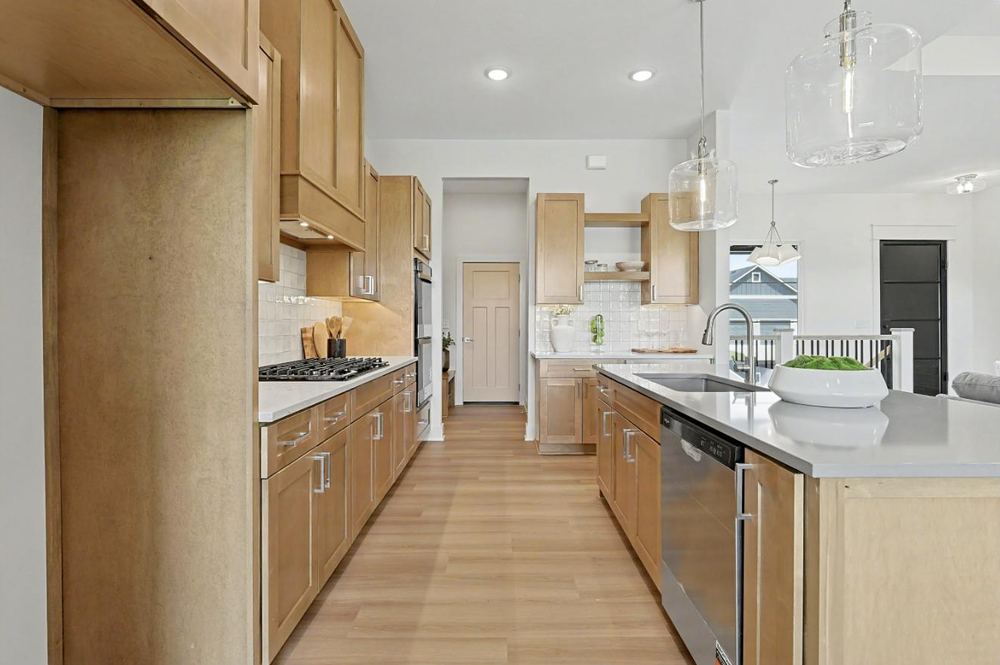 Kitchen island with a prep sink and quartz-look counter at 3117 Sunflower Drive, looking through to the rear hall – Derby, KS