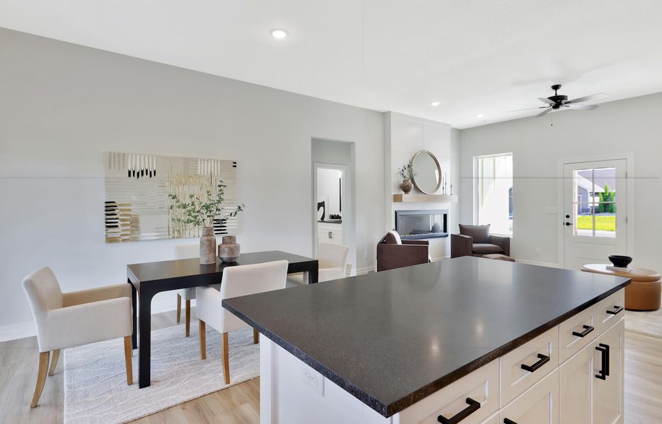 Dining area at 517 S Sweetwater Road beside the kitchen island, looking through to the living room fireplace – Maize, KS
