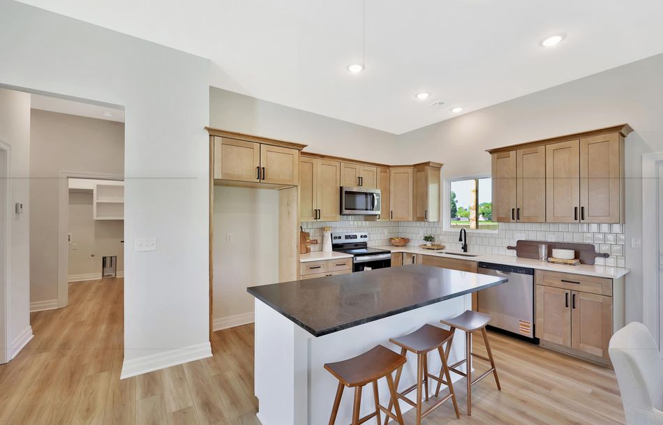 Kitchen at 517 S Sweetwater Road with natural maple cabinetry, a honed black island top and white subway tile – Maize, KS