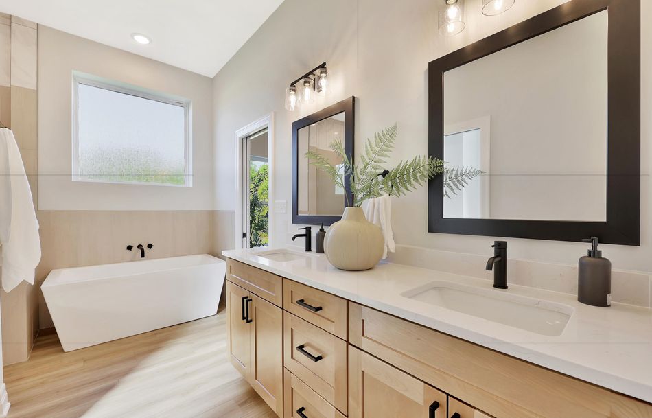 Primary bathroom at 517 S Sweetwater Road with a freestanding tub, maple double vanity and black-framed mirrors – Maize, KS